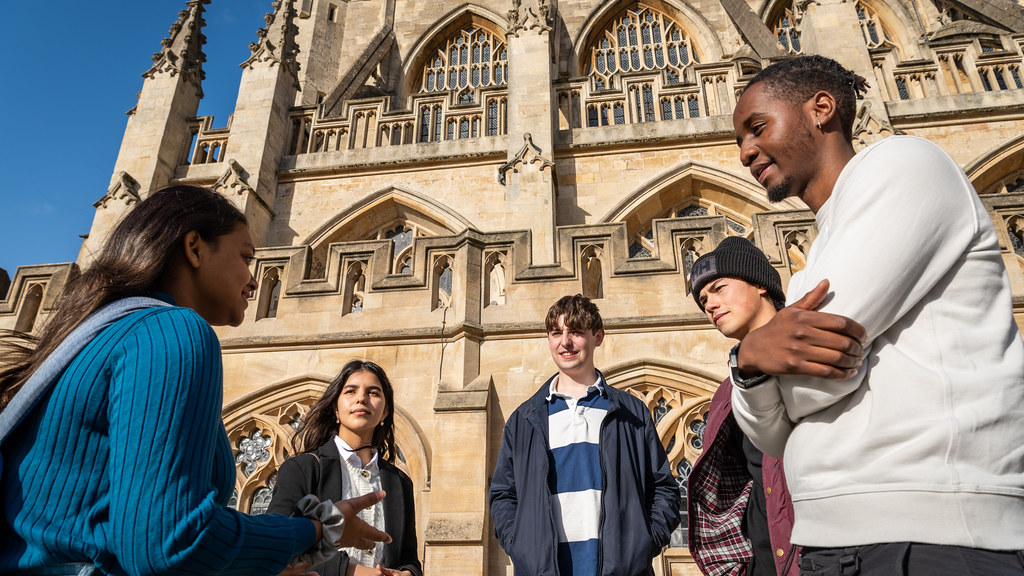 A group of people talking in front of Bath Abbey.